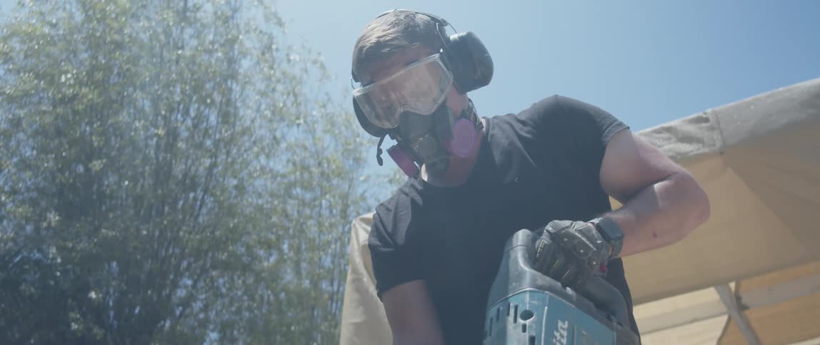 Man uses a jackhammer to demolish an outdoor brick floor