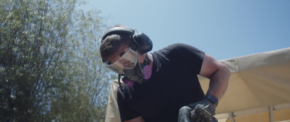 A worker in heavyduty boots operates a jackhammer breaking up concrete