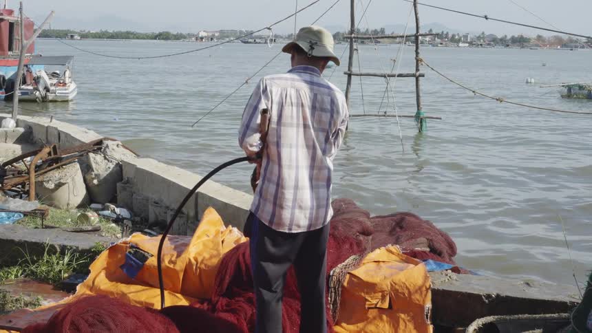 Man with a hose washing a red tarp