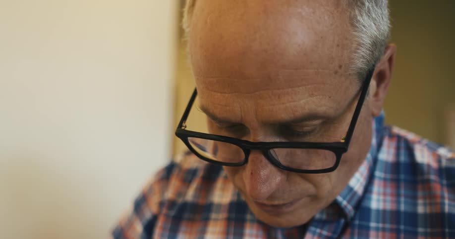 An older man with glasses focuses while cooking