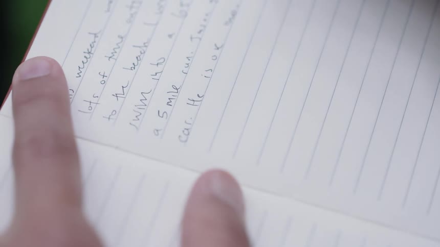 A white person using a pen to write in a notebook