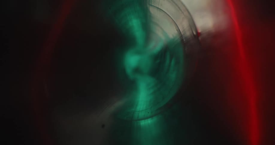Green and red lights shine through a transparent glass cylinder