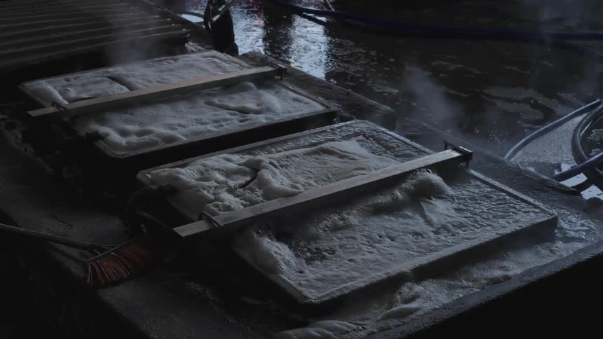 Rectangular metal structures on a damp surface covered in foam with water being heated