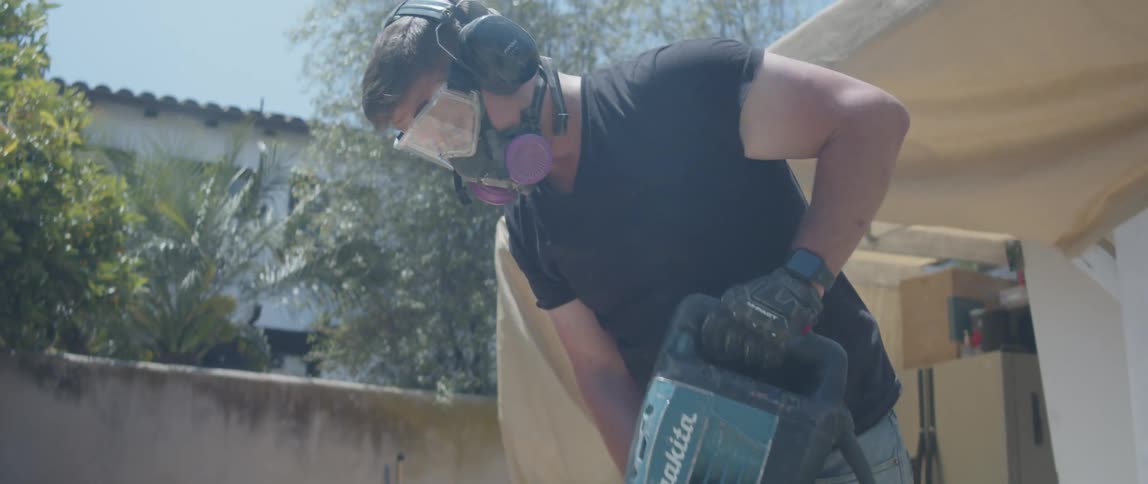 A worker is breaking the bricks with a jackhammer