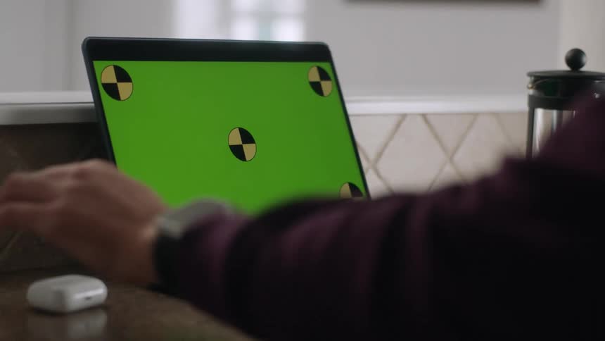 A persons hands typing on a laptop with a green replaceable screen