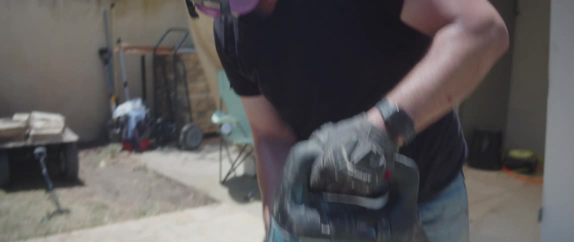 A construction worker uses a jackhammer to break up a patio