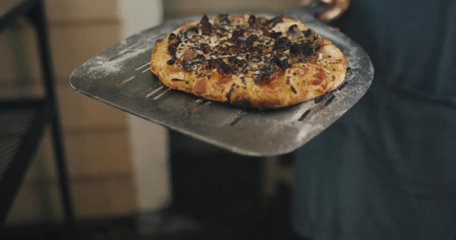 A man presenting a freshly cooked pizza