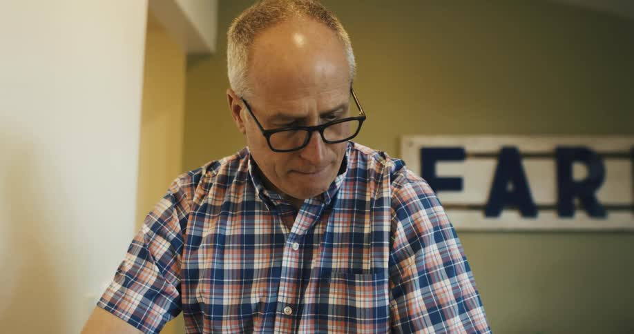 Man standing in a room with a sign on the wall concentrates on a task