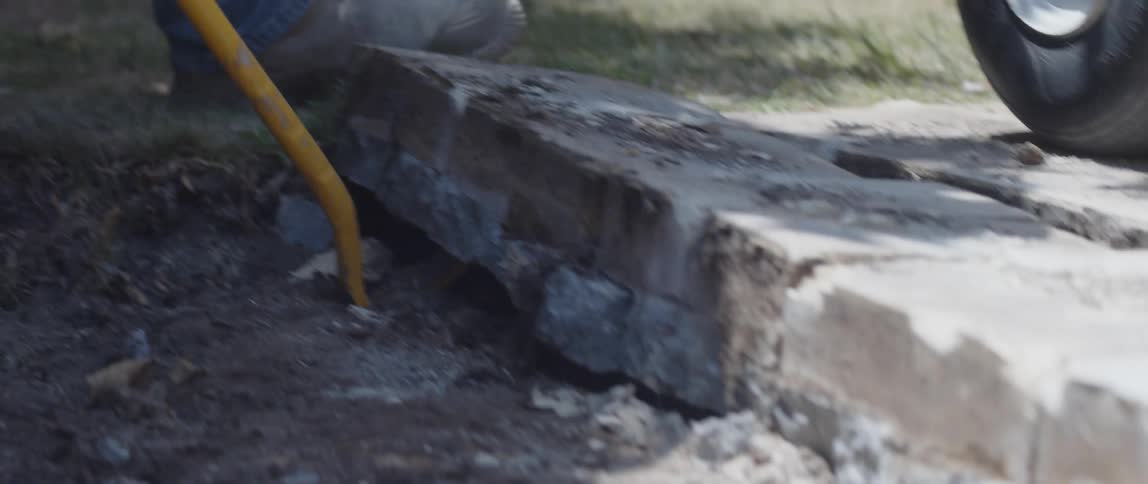 Closeup of a man removing concrete stones from a damaged sidewalk