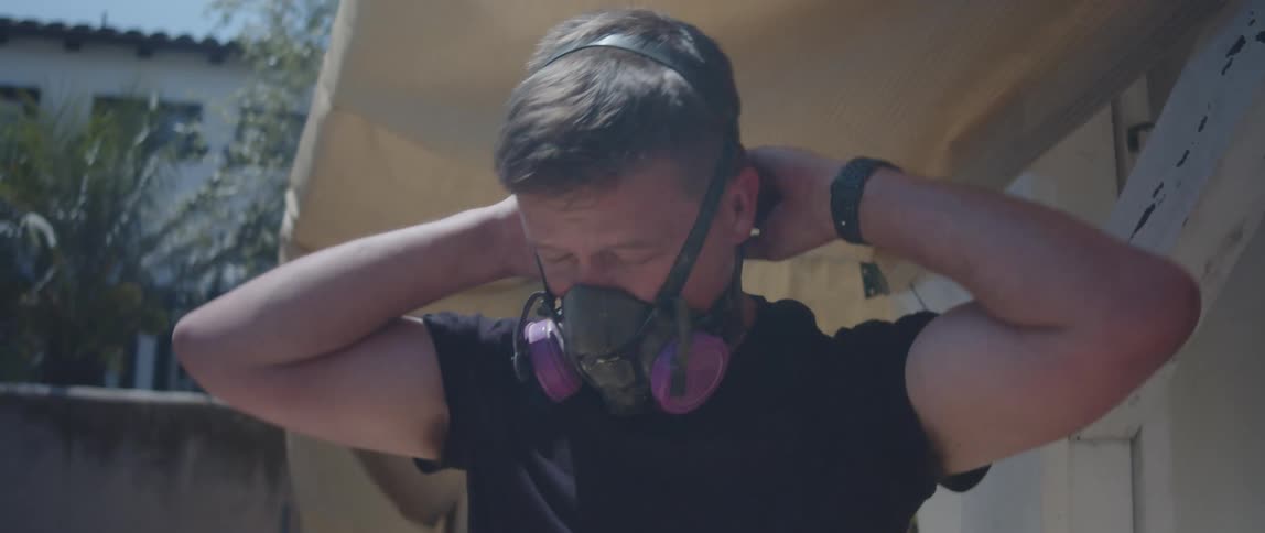 A man removes his mask outside