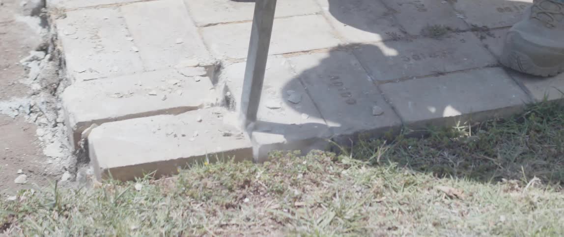 A worker in heavyduty boots operates a jackhammer breaking up concrete