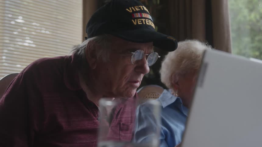 Concentrated elderly man sitting typing on a laptop