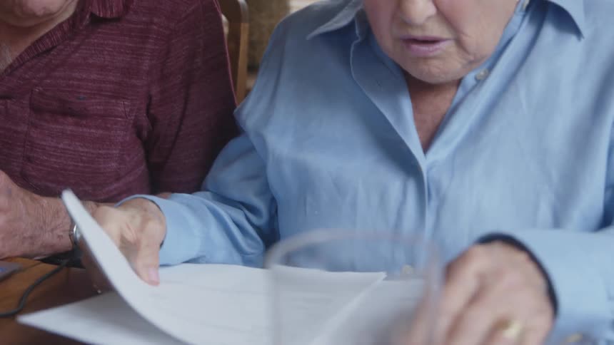 Elderly couple sitting at a table checking some documents