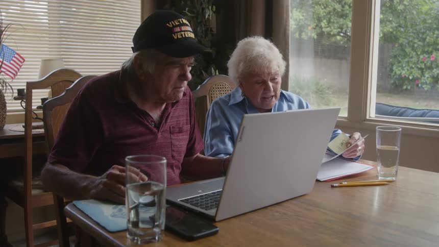 A man and woman talk while using a laptop