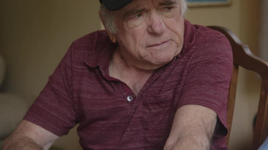 Elderly couple sitting with their hands together with a sad facial expression