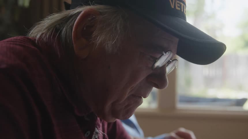 A man is typing on a laptop as a woman goes through papers