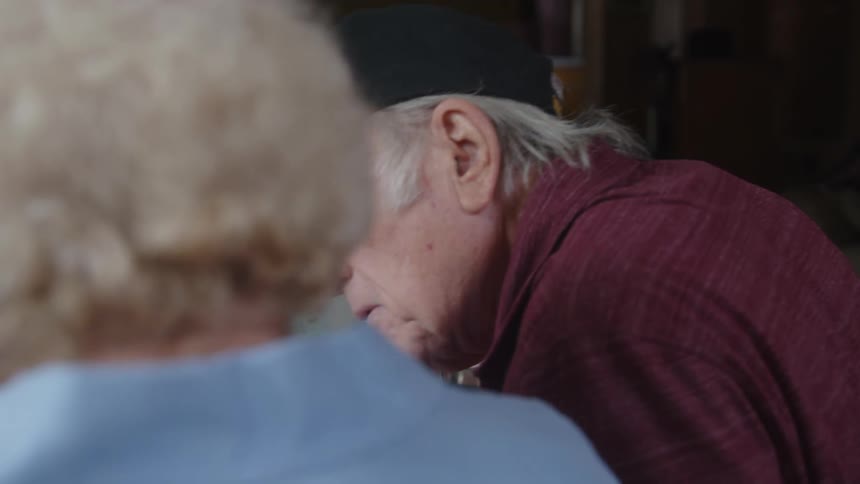 Elderly man and woman sitting talking with a laptop at the table