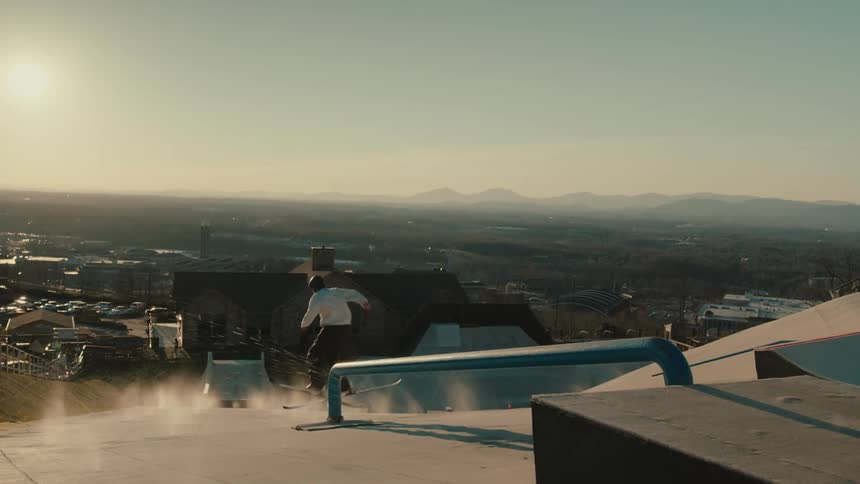 A skier jumps up on a pipe and slides off to continue down the hill