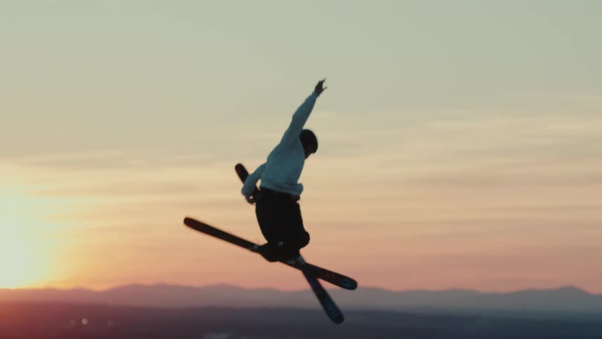 Man snowboarding at dusk jumping from a slope