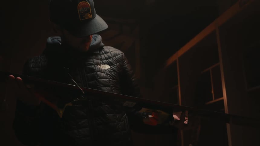 An individual in a dimly lit room examines a colorful ski