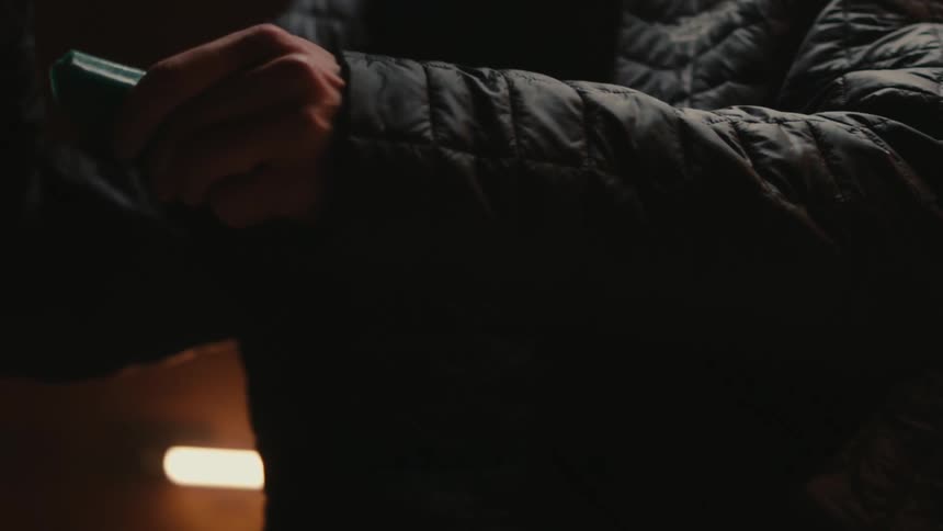 Mans hands holding an iron and a tablet inside a room with low lighting