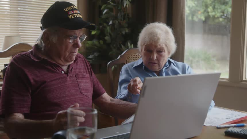 Two elderly people sitting at the table talking looking at documents and with an expression of excitement on their faces