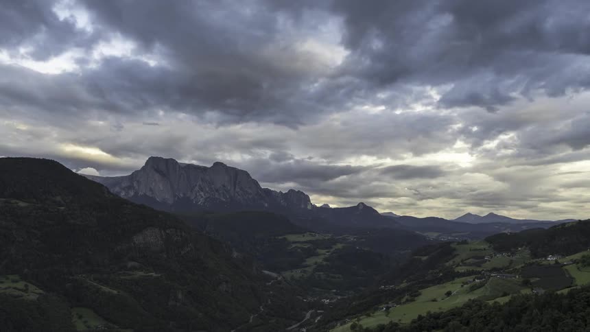Wide landscape of mountains with imposing peaks in the background and green valleys in the foreground and the day is dusk