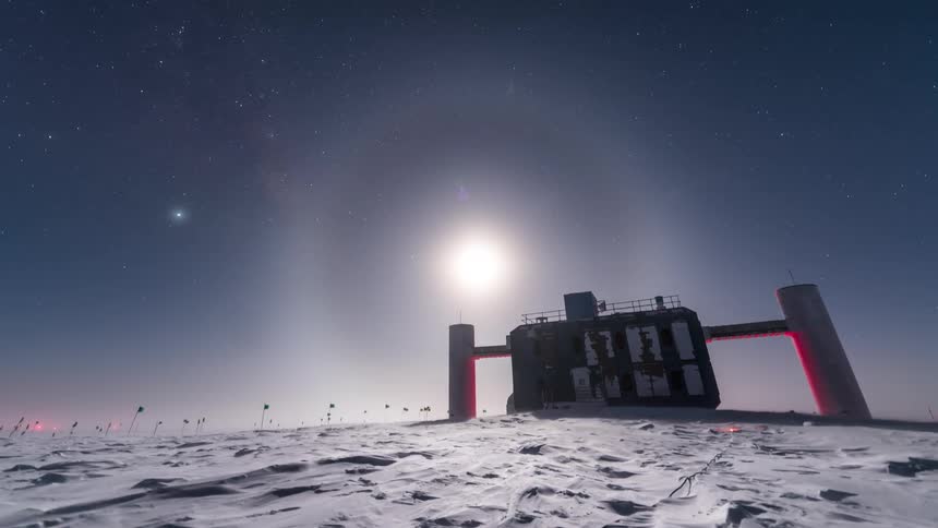 Landscape with the dusk sky above a snowy terrain highlighting observatory structures and the sky with aurora borealis and stars