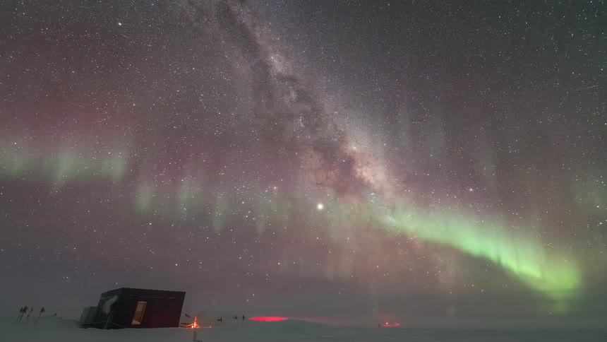 Time lapse of a starfilled night sky with vibrant northern lights over a scientific research station in the arctic