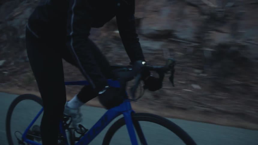 Person cycling on a road with vegetation around