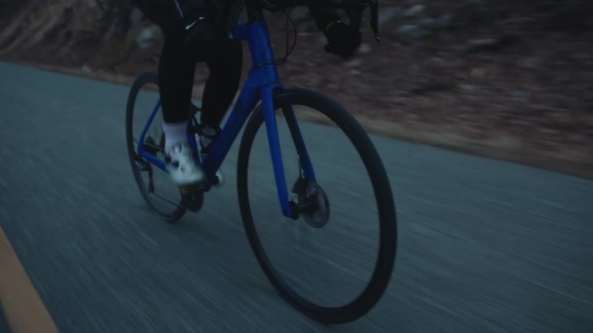 Cyclist man cycling on a paved street with nature around