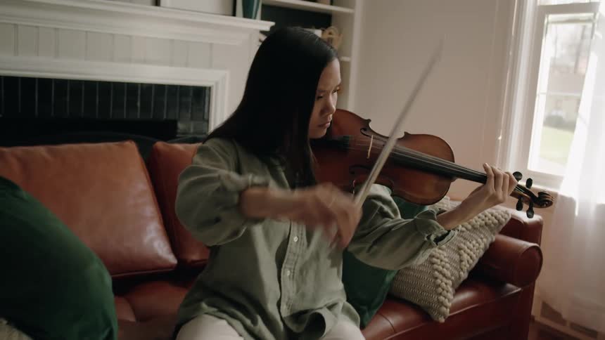 Young woman sitting on a sofa playing a violin