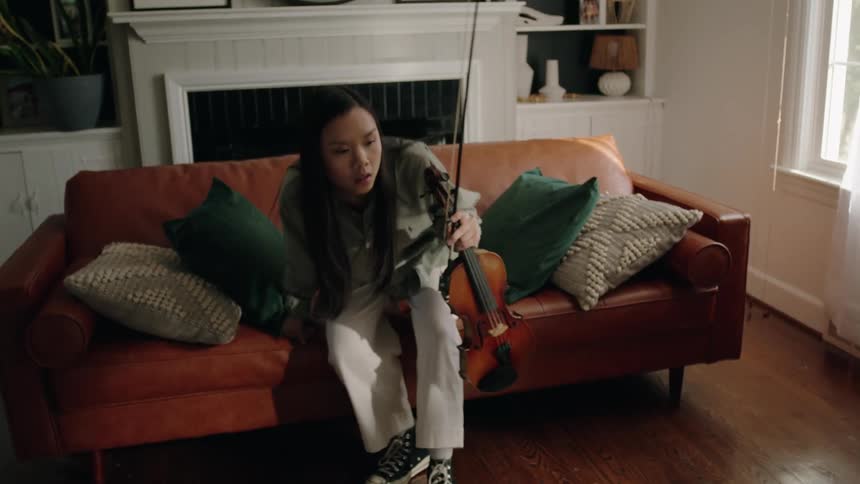 Woman sitting on a sofa holding a violin