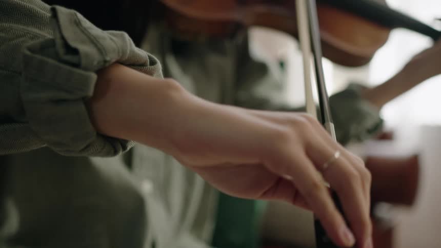 An asian female musician plays a violin in a living room