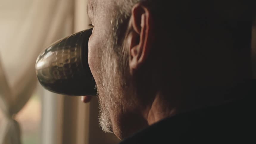 Side portrait of a bearded man drinking a cup
