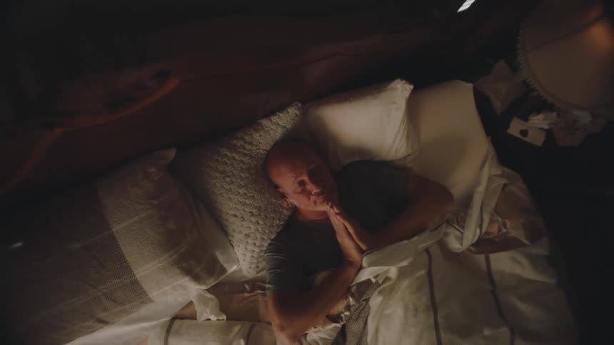 Overhead view of a man laying in bed waking up