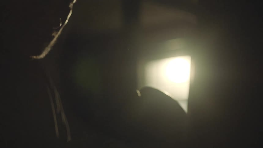 Silhouette of a boxer hitting a punching bag on a dimly lit room
