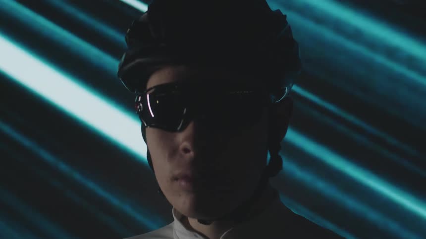 Portrait of a man with a cyclists helmet and glasses against a blue background