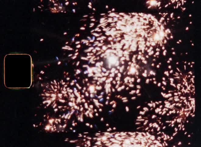 The bright full moon shines in the night sky on New Years Evening as aerial fireworks explode and the rockets fly up causing golden sparkles and flickering light