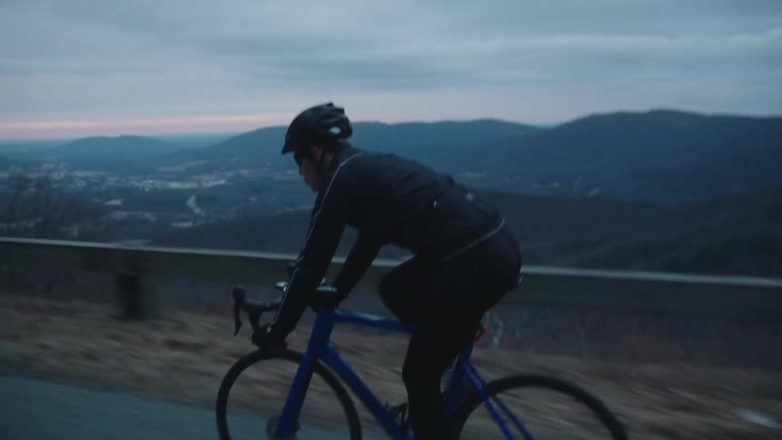 Cyclist cycling on a street with the silhouette of mountains in the background