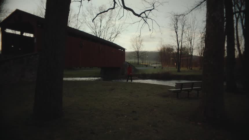 Female runner stops near the river in a rural park after dusk