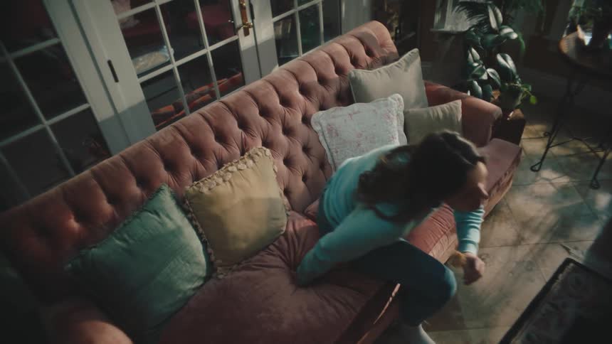 Young man and woman getting up from the sofa while holding a rose with their hands