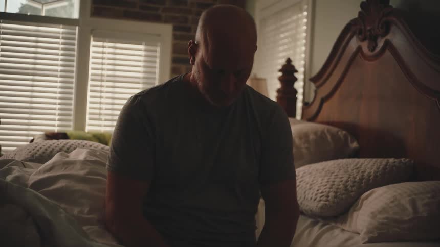 Man sitting on the bed with his head down