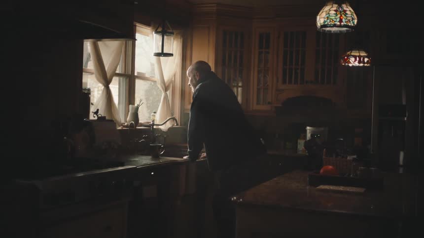 Man walking in the kitchen and picking up a cup