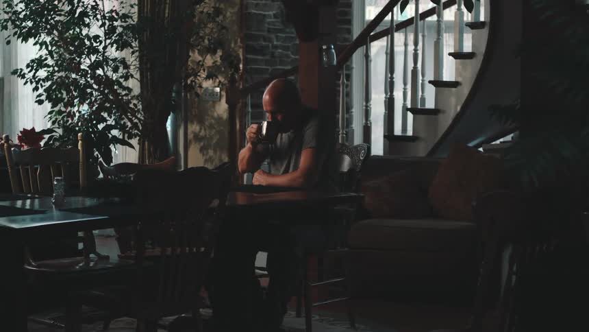 A man is drinking coffee at his dining room table