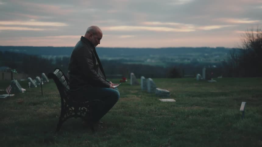 A man is holding a piece of paper in the graveyard