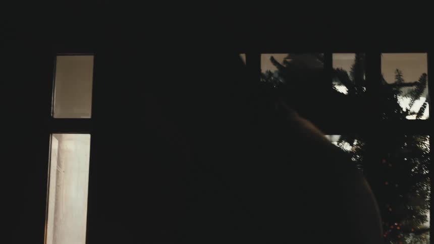 Silhouette of a man putting on a jacket before leaving the house at morning