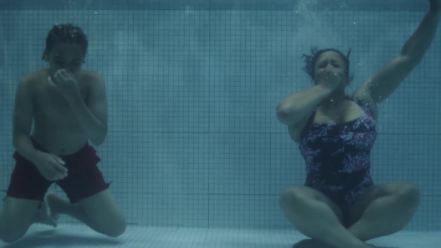 Two people dive under the pool water