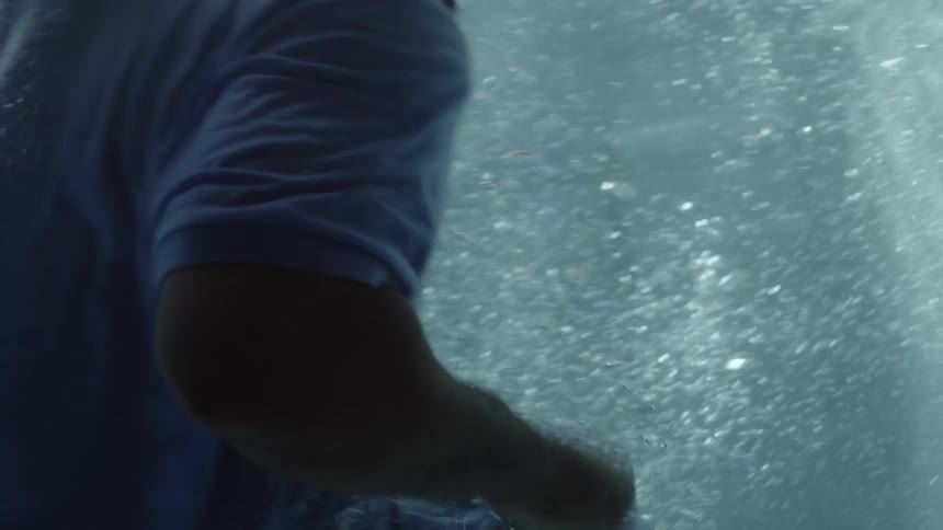 A black person drops into a pool and swims to the surface