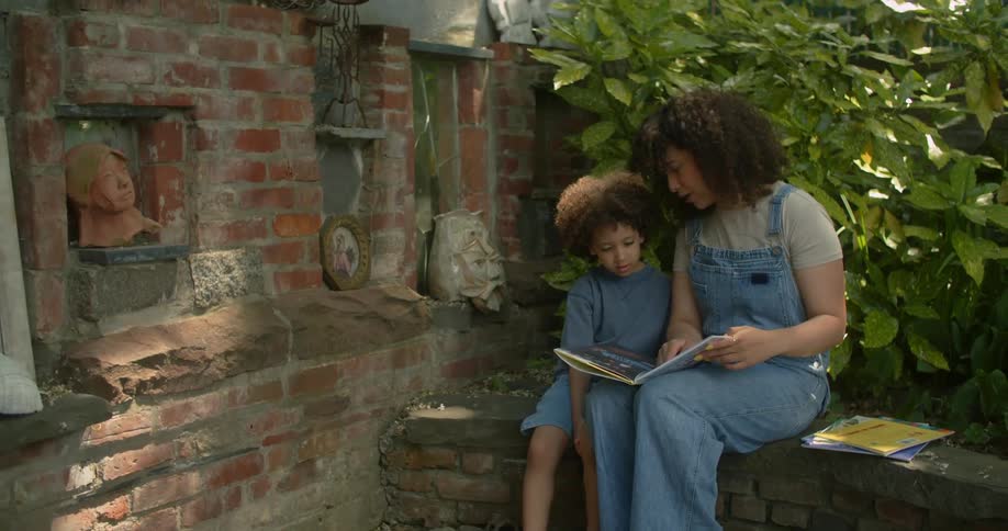 A mother is reading to her son outside